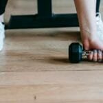 Faceless young woman lifting dumbbell during workout in gym