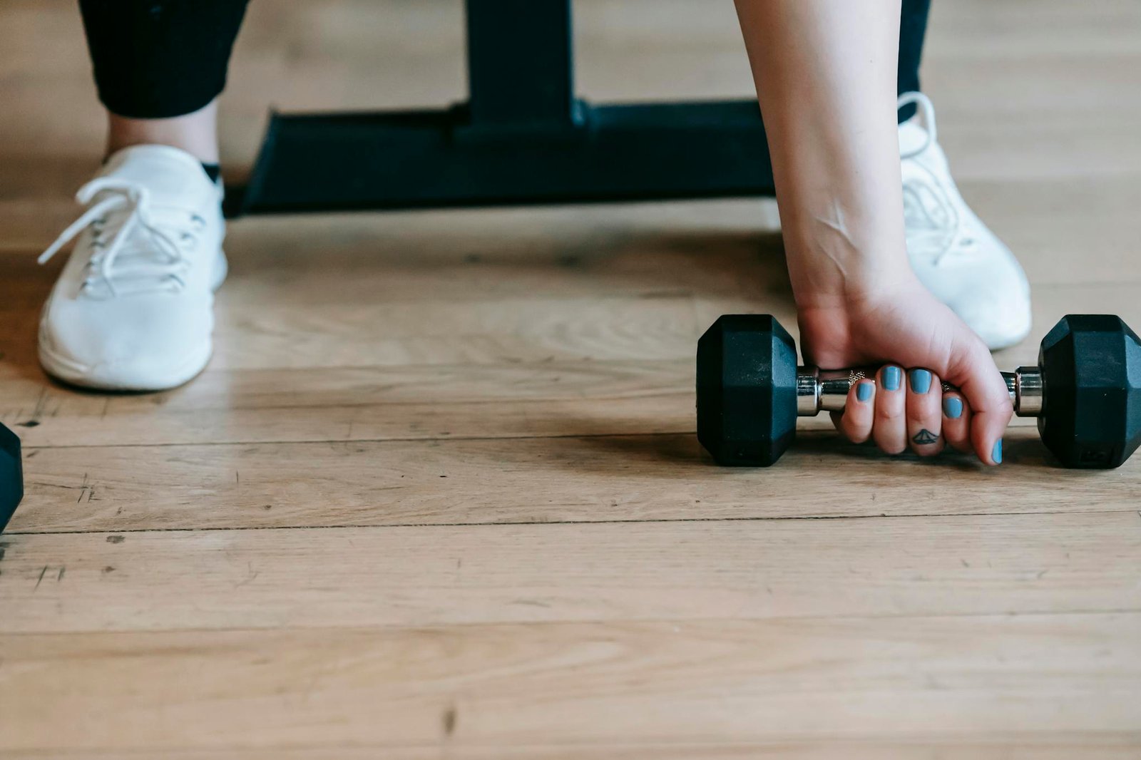 Faceless young woman lifting dumbbell during workout in gym